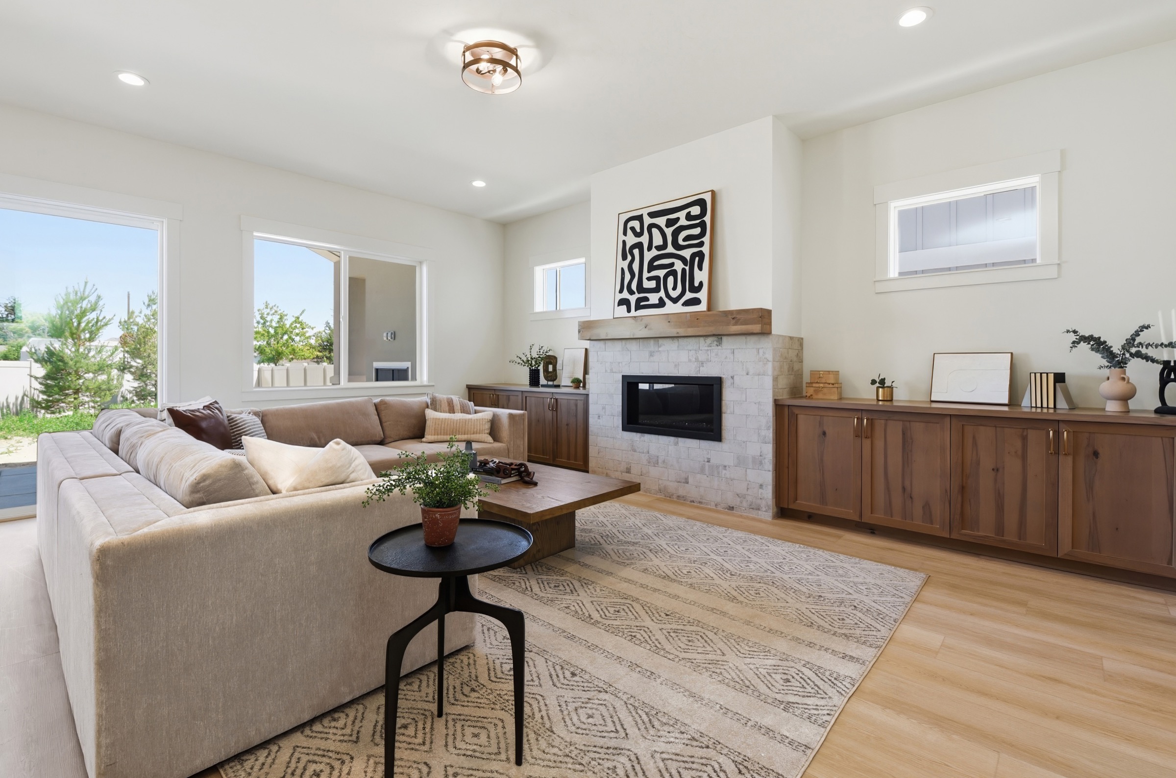 Bright great room with warm wood built-ins, a stone fireplace, and layered neutral furnishings