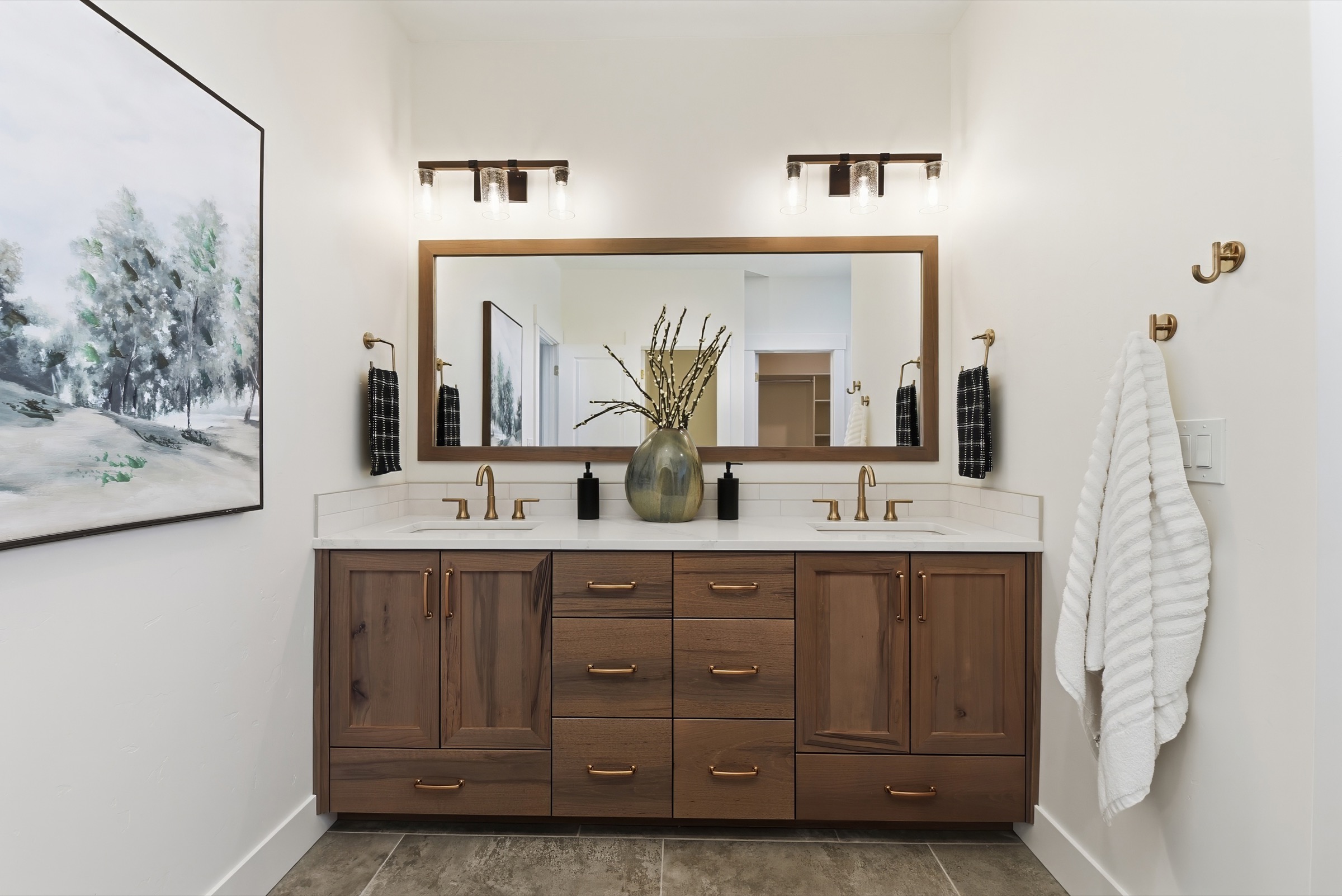 Walnut double vanity with a wide framed mirror and warm brass fixtures