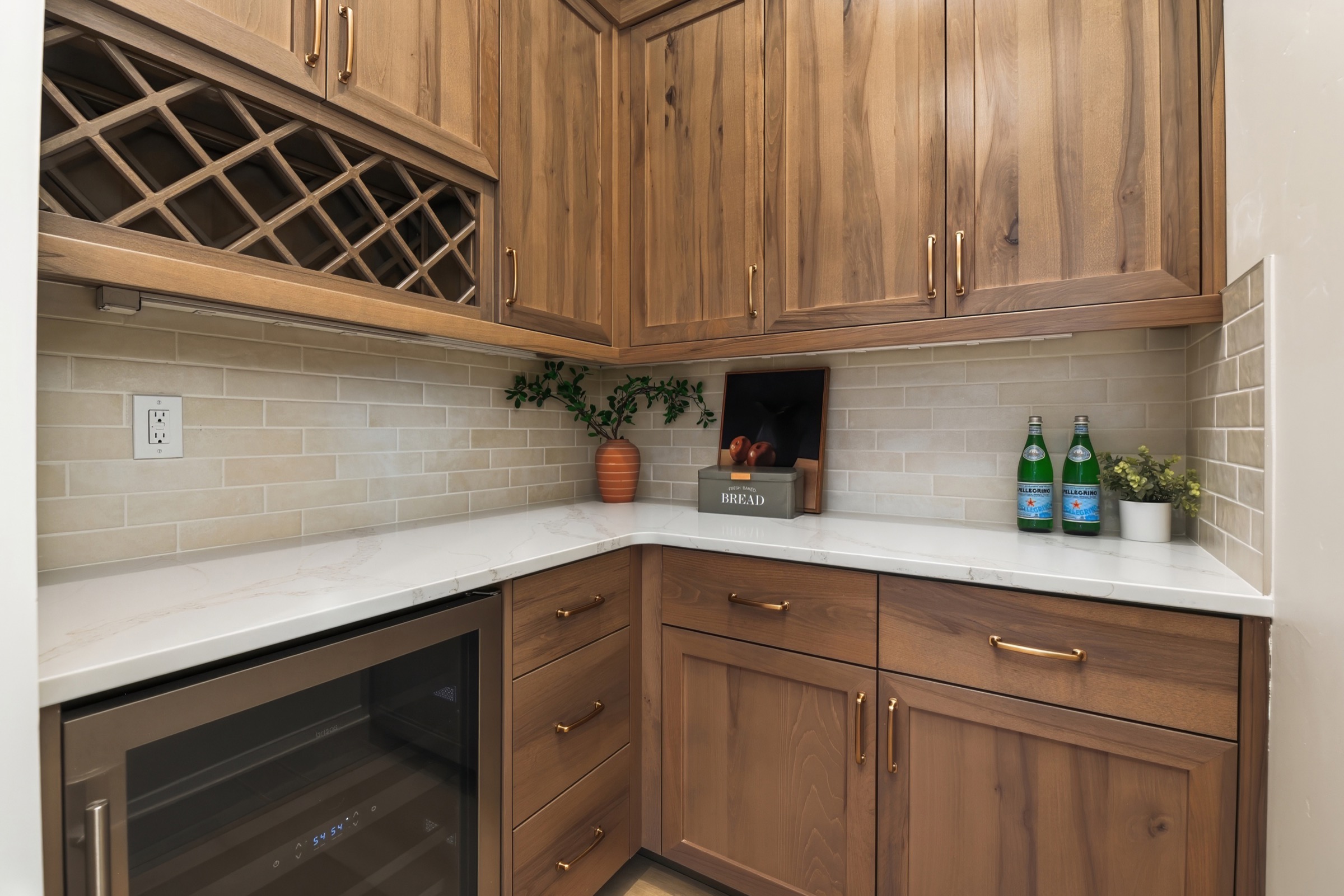 Custom walnut wine room with bottle storage, stone counters, and brass hardware